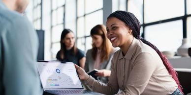 Professional presenting investment data on a laptop in a meeting
